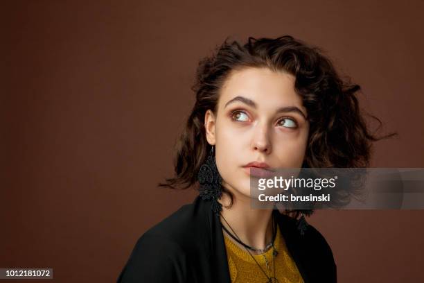 close-up portrait of a young beautiful woman with curly hair in the studio on a brown background - lithuania woman stock pictures, royalty-free photos & images