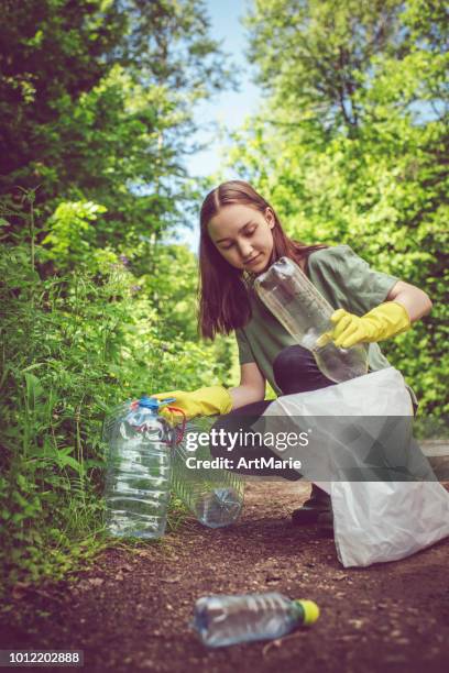 jeune fille bénévole recueille les bouteilles en plastique à l’extérieur - adult girl single park photos et images de collection