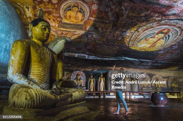 young woman explores buddhist temple, in cave - dambulla stock pictures, royalty-free photos & images