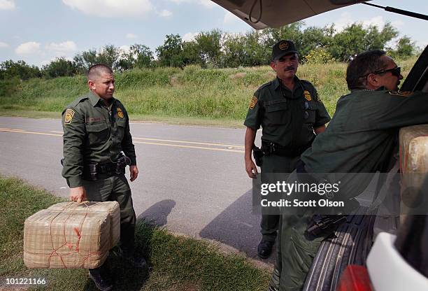 Border Patrol agents load bales of marijuana into their SUV after it was seized from a smuggler near the Mexican border on May 27, 2010 near McAllen,...