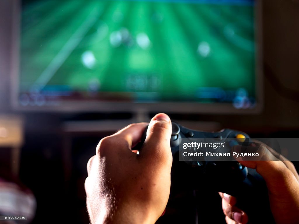 Close up young man with joystick controller for console playing sport simulator video game on large screen