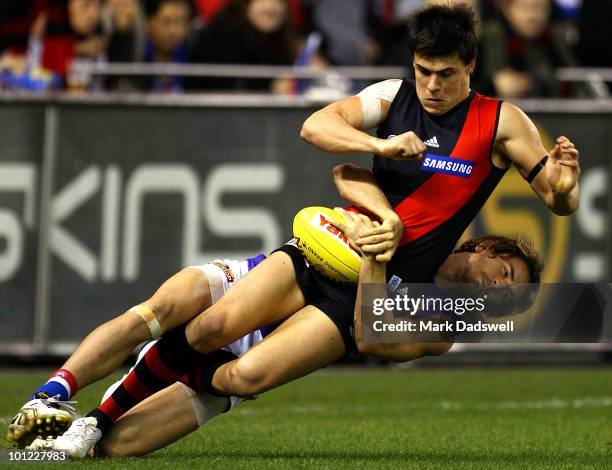 Angus Monfries of the Bombers is wrapped up in a tackle by Dylan Addison of the Bulldogs during the round 10 AFL match between the Essendon Bombers...