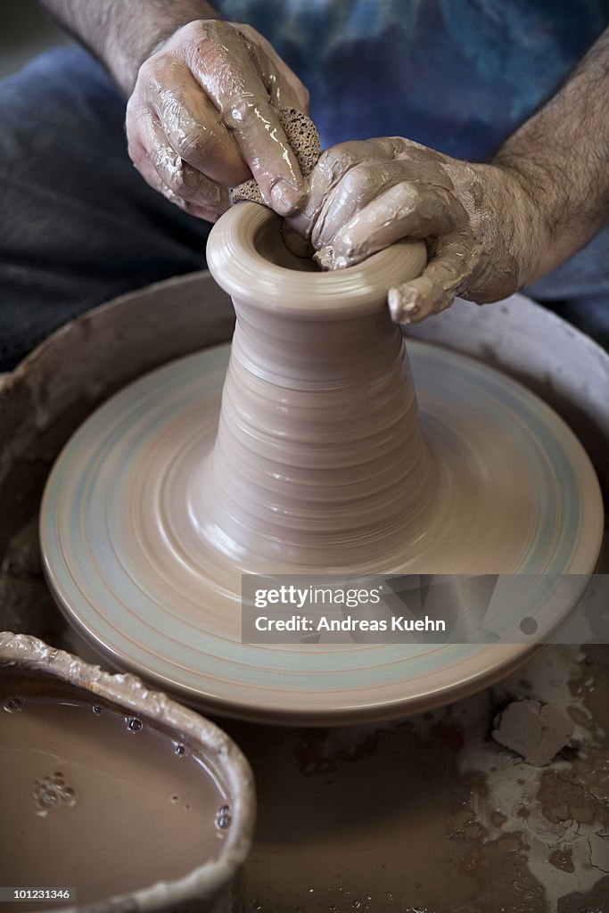 Potter throwing clay on potter's wheel.