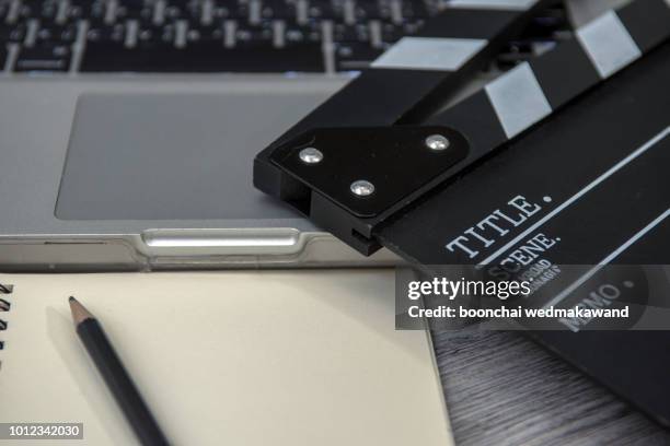 office stuff with movie clapper laptop and coffee cup pen notepad on the wood table top view shot.dark effect - scenario stockfoto's en -beelden