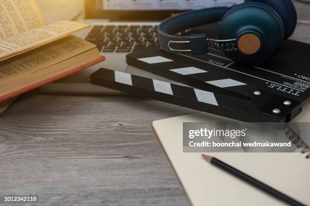 office stuff with movie clapper laptop and coffee cup pen notepad on the wood table top view shot.dark effect - top producer stock pictures, royalty-free photos & images