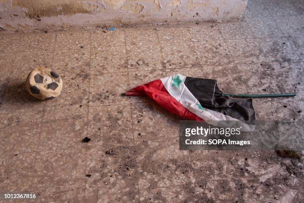 The flag of the Syrian regime appears on the ground next to a child's ball in Al-Foah after the government agreed to release 1500 rebel prisoners in...