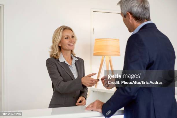 receptionist receiving business card from businessman - blue blazer stock pictures, royalty-free photos & images