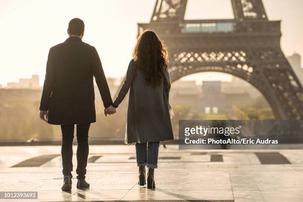 couple holding hands near eiffel tower - couple paris tour eiffel trocadero stock-fotos und bilder