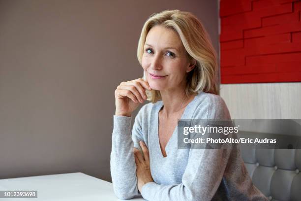 smiling woman sitting in cafe - mano-en-la-barbilla fotografías e imágenes de stock