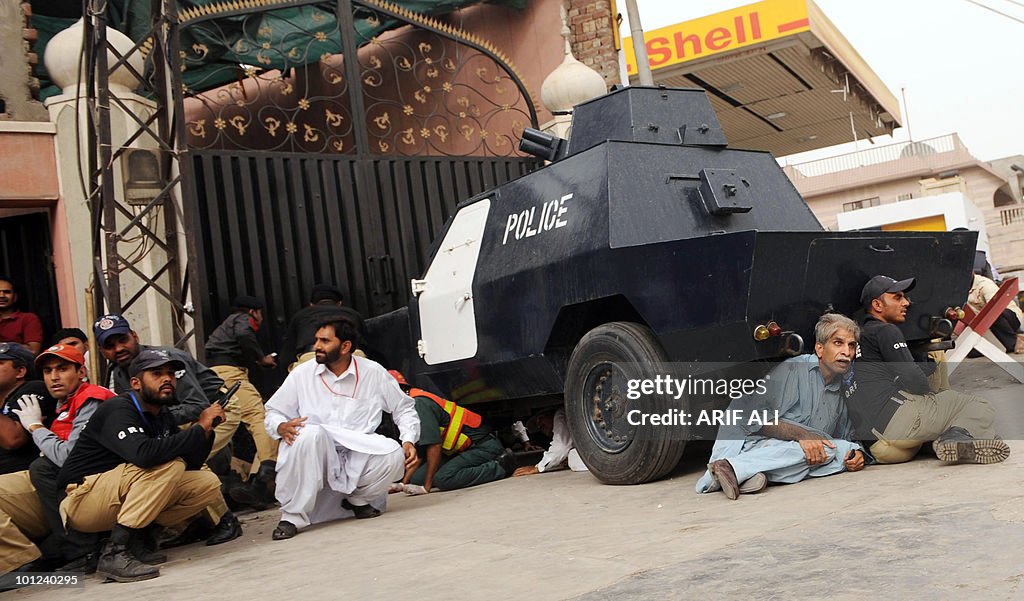 Pakistani police take cover outside one