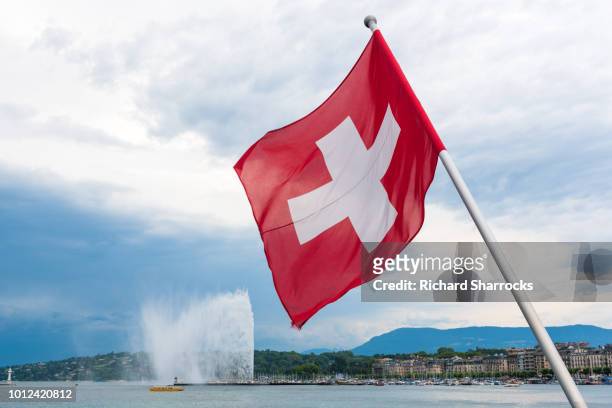 swiss flag and jet d'eau in geneva, switzerland - swiss flag stock pictures, royalty-free photos & images