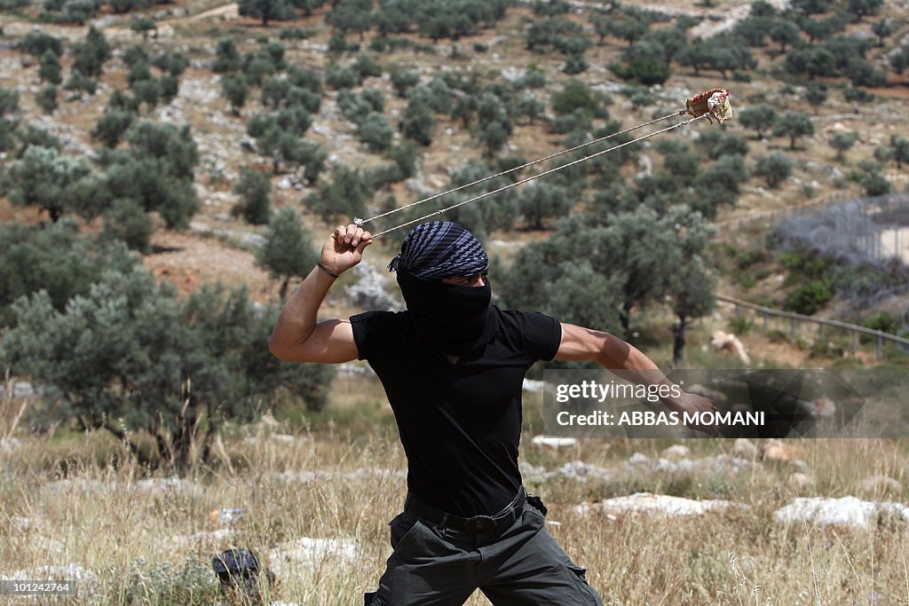 A Palestinian youth hurls a stone toward