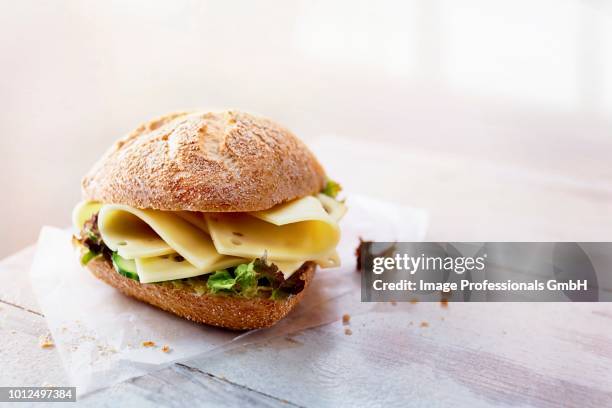 a rye bread roll with cheese and lettuce - krulandijvie stockfoto's en -beelden