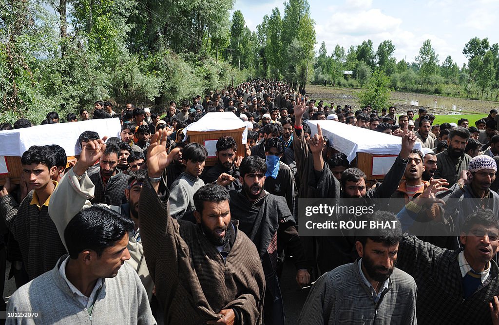 Kashmiri men carry the coffins of three