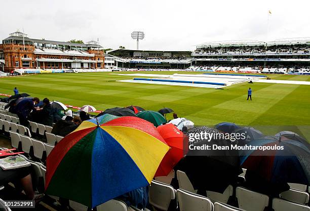 Fans brave the weather with their umbrellas as rain falls during day 3 of the 1st npower Test between England and Bangladesh played at Lords on May...