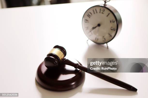 gavel and table clock on desk - procedimento giudiziario foto e immagini stock
