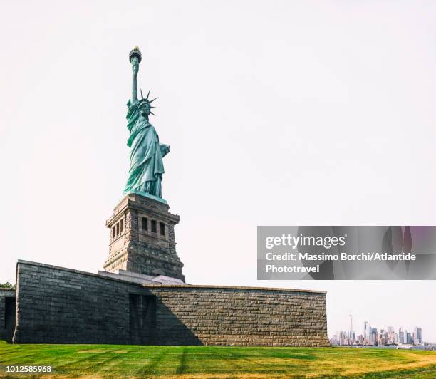 liberty island, the statue of liberty, manhattan with the one world trade center skyscraper on the right - insel liberty island stock-fotos und bilder