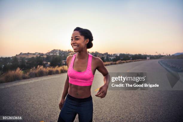 portrait of happy female athlete standing on road - skinny black woman - fotografias e filmes do acervo