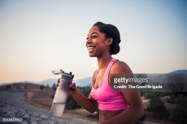 happy female runner holding water bottle - women running fotografías e imágenes de stock