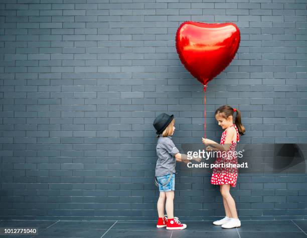two children with heart shape air balloon - sweet little models stock pictures, royalty-free photos & images