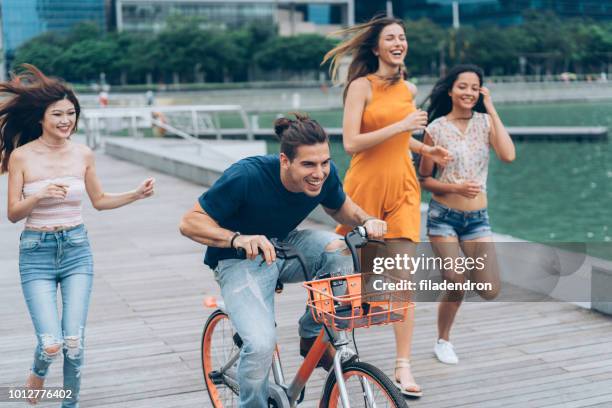 make fun together riding bicycle - male with group of females stock pictures, royalty-free photos & images