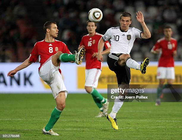 Lukas Podolski of Germany and Krisztian Vadocz of Hungary battle for the ball during the international friendly match between Hungary and Germany at...