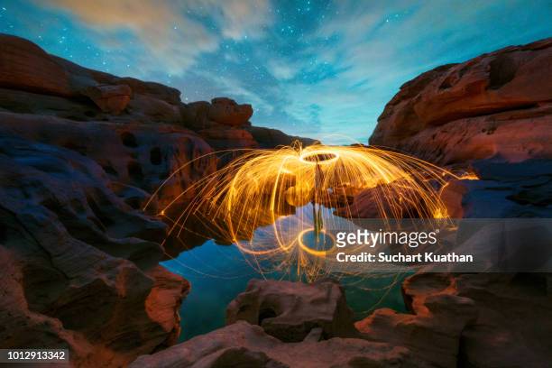 spinning burning steel wool with water reflection and stars on blue sky at sam pan bok, grand canyon of thailand, - rocky star stock pictures, royalty-free photos & images