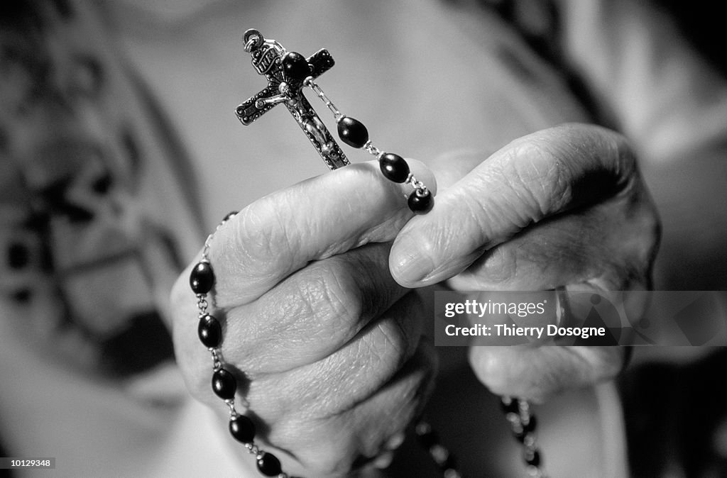 CLOSE UP OF HANDS WITH ROSARY