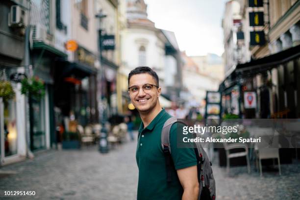 young handsome man with backpack on the street of the old town - bukarest city stock-fotos und bilder