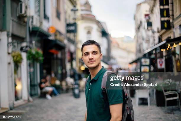 young handsome man with backpack on the street of the old town - bukarest city stock-fotos und bilder