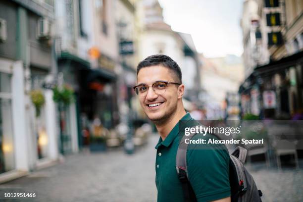 young handsome man with backpack on the street of the old town - romania people stock pictures, royalty-free photos & images