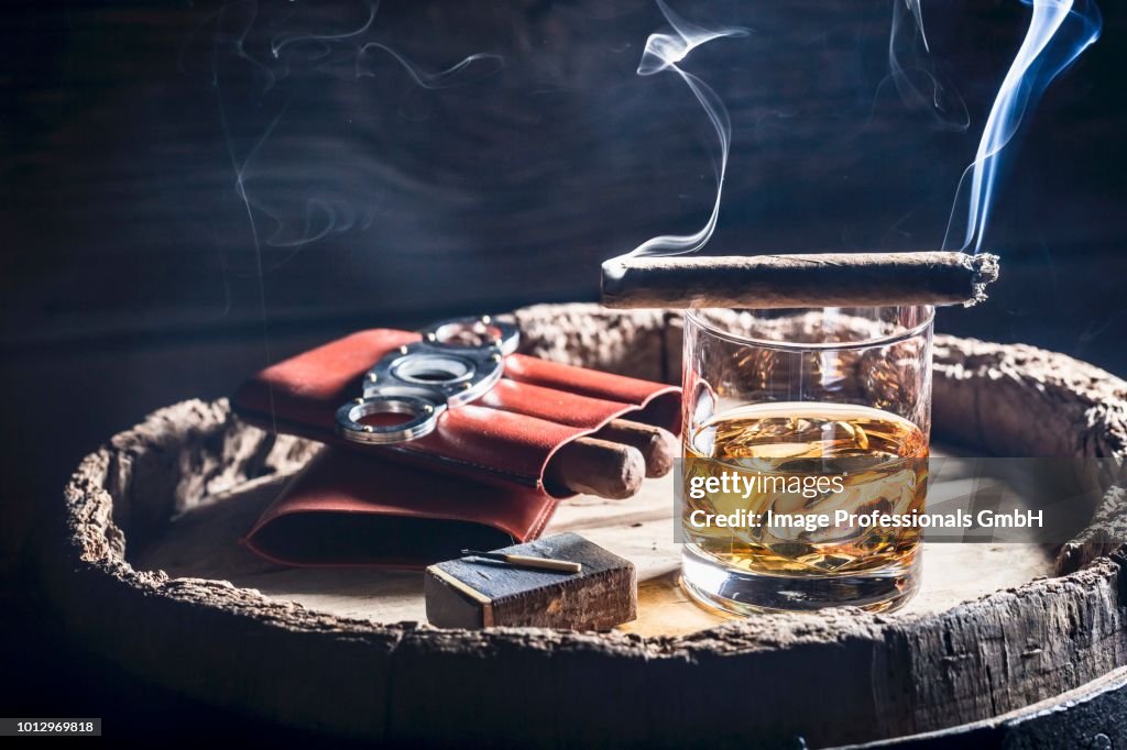 A smoking cigar over a glass of whiskey