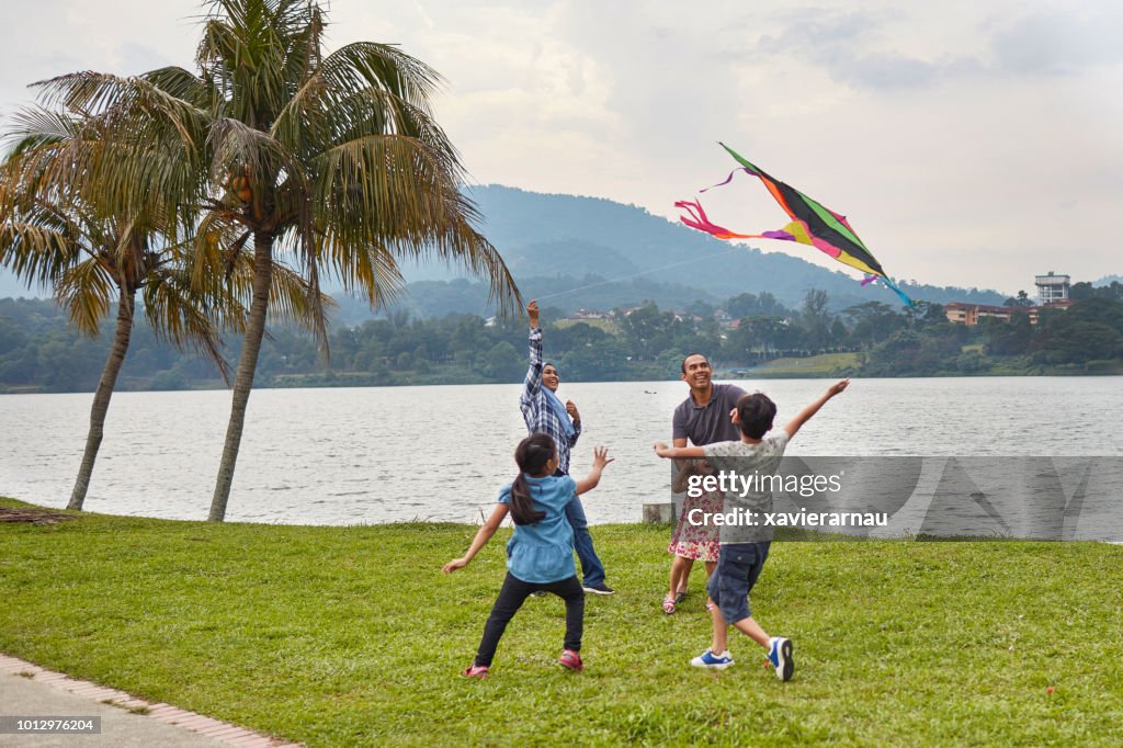 Mother flying kite with family at lakeshore