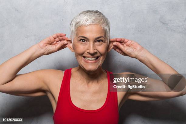 stupida donna matura che fa un viso e tira le orecchie - pull a face foto e immagini stock