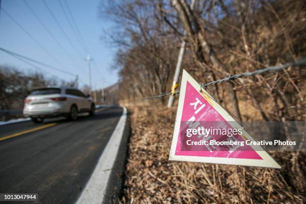 a sign reading "mine" is displayed next to a road - north korea stockfoto's en -beelden