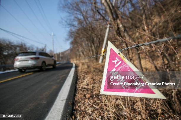 a sign reading "mine" is displayed next to a road - north south korea stock pictures, royalty-free photos & images
