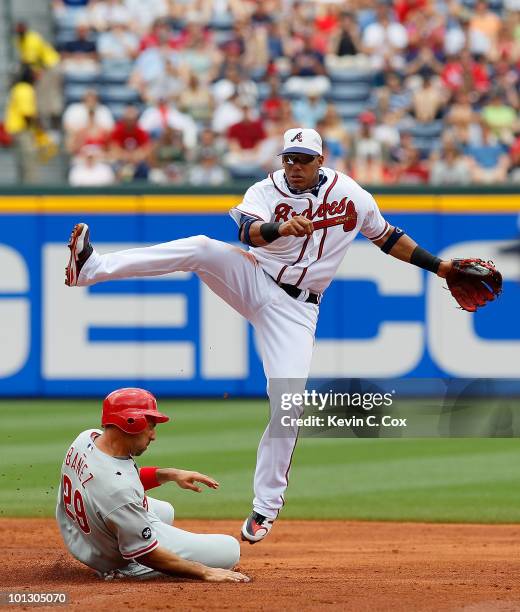 Yunel Escobar of the Atlanta Braves leaps as he turns a double play over Raul Ibanez of the Philadelphia Phillies at Turner Field on May 31, 2010 in...