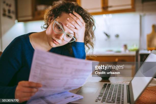 woman going through bills, looking worried - problems imagens e fotografias de stock