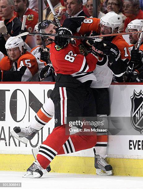 Tomas Kopecky of the Chicago Blackhawks checks Mike Richards of the Philadelphia Flyers into the Flyers bench in the first period of Game Two of the...