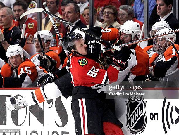 Tomas Kopecky of the Chicago Blackhawks checks Mike Richards of the Philadelphia Flyers into the Flyers bench in the first period of Game Two of the...