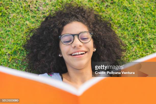 meisje liggend op het gras en lezen van een boek - teenager learning child to read stockfoto's en -beelden