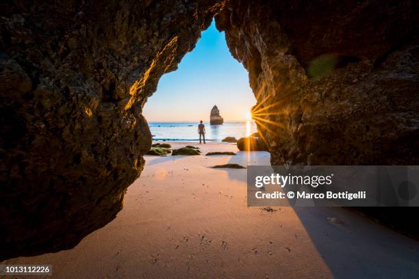 man looking at view on the beach at sunrise, algarve, portugal - distrito de faro portugal fotografías e imágenes de stock
