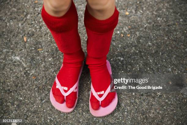 low section of girl wearing red socks and flip flops - flip flop stock pictures, royalty-free photos & images