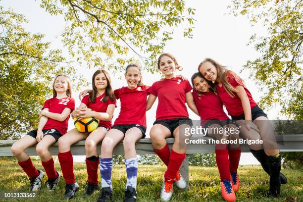 portrait of girls soccer team sitting on bench in park - soccer bench stock pictures, royalty-free photos & images
