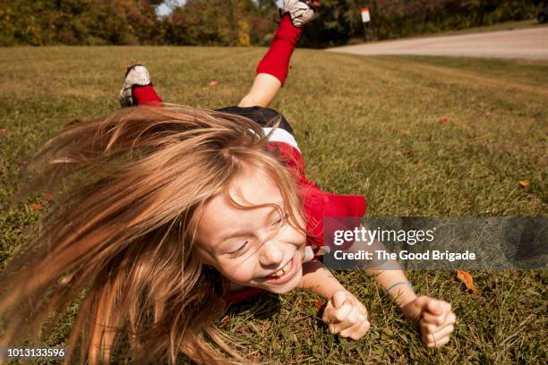 girl rolling on grass at park - rolling stockfoto's en -beelden