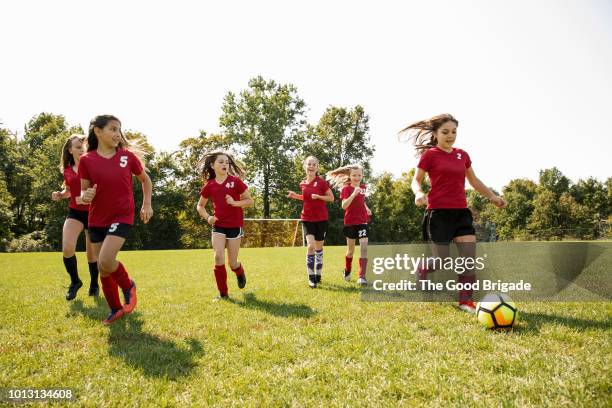 girl soccer team practicing on grassy field - sport di squadra foto e immagini stock