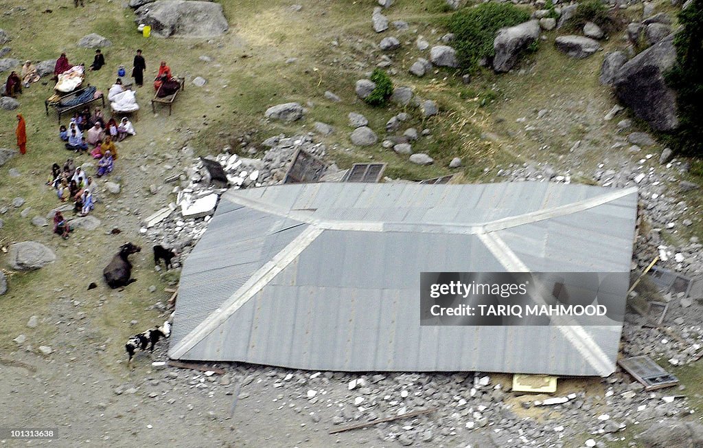 Homeless Pakistani people sit beside the