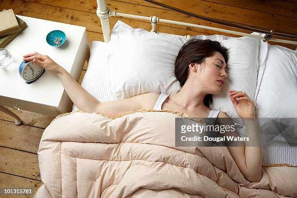 woman in bed switching alarm off. - above view of man sleeping on bed stock-fotos und bilder