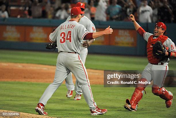 Pitcher Roy Halladay of the Philadelphia Phillies is congratulated by teammates Carlos Ruiz and Ryan Howard after pitching a perfect game against the...