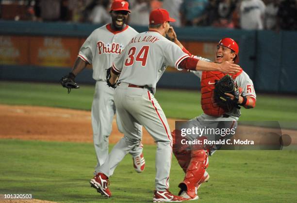 Pitcher Roy Halladay of the Philadelphia Phillies pitches celebrates with teammates Carlos Ruiz and Ryan Howard after pitching a perfect game against...